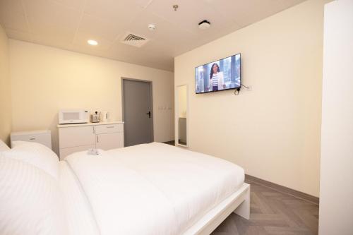 a bedroom with a white bed and a tv on the wall at Riggae Tower Hotel in Kuwait