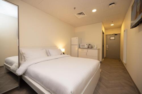 sypialnia z dużym białym łóżkiem i kuchnią w obiekcie Riggae Tower Hotel w Kuwejcie