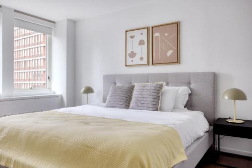 a white bedroom with a large bed with two lamps at Back Bay 2br w gym nr Prudential Center BOS-299A in Boston