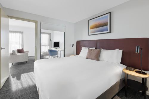 um quarto de hotel com uma cama grande e uma sala de estar em Quest Werribee em Werribee