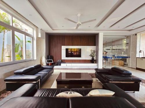 a living room with leather couches and a tv at RUBY 2 LUXURY VILLA by NEST GROUP in Nha Trang