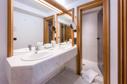 a bathroom with two sinks and two mirrors at Sonnenalp Resort in Ofterschwang