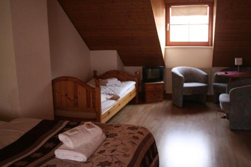 a bedroom with two beds and a tv and a chair at Landgasthof Hotel Rebe Alzey in Alzey