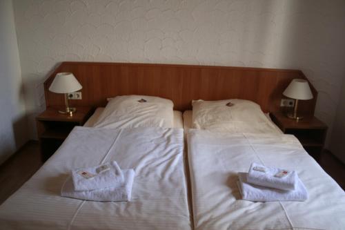 two towels on a bed with two night stands at Landgasthof Hotel Rebe Alzey in Alzey
