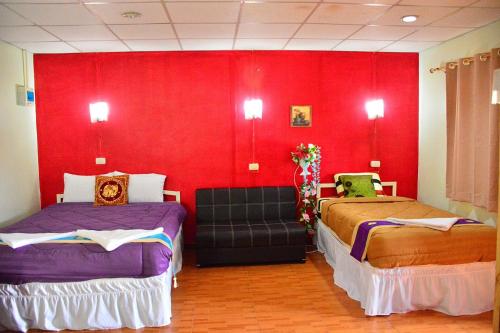 a room with two beds and a red wall at Thai Garden​ Resort​ Kanchanaburi​ in Kanchanaburi