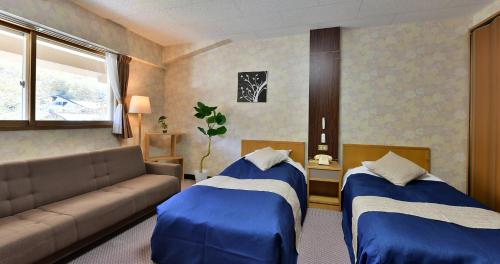 a living room with two beds and a couch at Shiga Grand Hotel in Yamanouchi