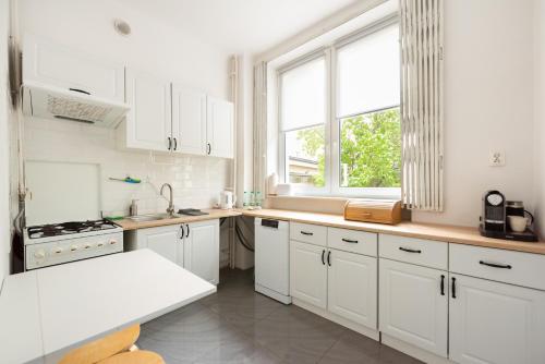 a kitchen with white cabinets and a large window at Plac Zbawiciela 3-Bedroom Apartment in Warsaw