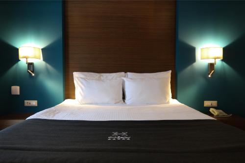 a bedroom with a bed with two lights on the wall at Hotel Dukagjini in Peje