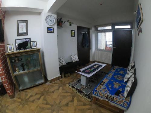 uma sala de estar com uma mesa e um relógio na parede em Blue Valley Apartment em Darjeeling