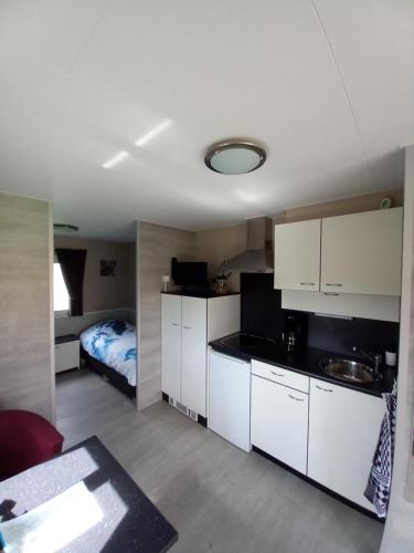 una cocina con armarios blancos y una cama en una habitación en Vakantiewoningen Ut Tumpke, en Kessel
