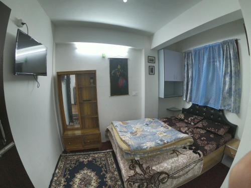 Dormitorio pequeño con cama y espejo en Blue Valley Apartment en Darjeeling