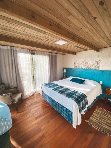 a bedroom with a large bed and a wooden floor at Cabana Mirim Estalagem Rural in Gramado