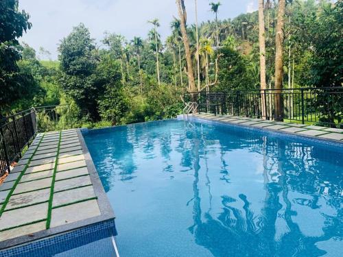een zwembad met blauw water en bomen op de achtergrond bij LetStay Vythiri Hill Palace in Vythiri