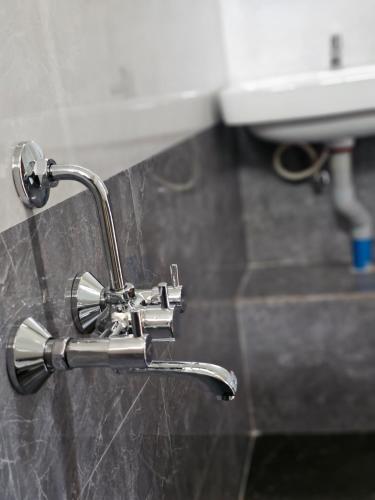 a silver faucet in a bathroom with a sink at Farmhouse with Pool - Kalavady Farmstay in Baindūru