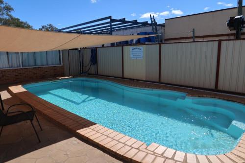 a large swimming pool with a large umbrella at Charleville Waltzing Matilda Motor Inn in Charleville