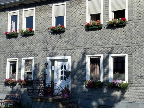 a gray brick house with flowers in windows at Rosenhaus Assinghausen in Olsberg