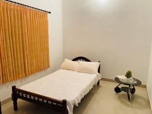 ein kleines Schlafzimmer mit einem Bett und einem Tisch in der Unterkunft Bethel inn in Mananthavady