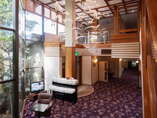 a lobby with a piano in the middle of a building at Tabist Sakura no Yakata Hotel in Fuefuki