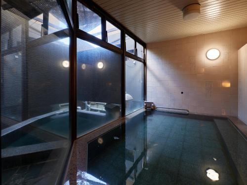 a bathroom with a tub and a glass wall at Tabist Sakura no Yakata Hotel in Fuefuki