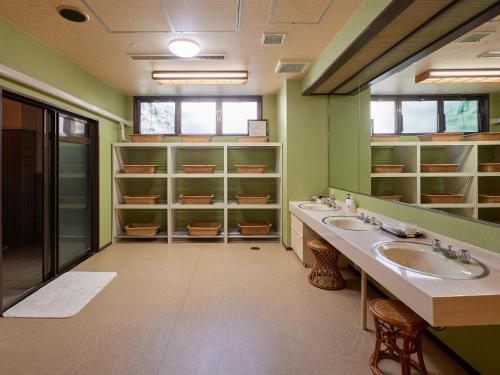 a bathroom with two sinks and green walls at Sakura no Yakata Hotel in Fuefuki