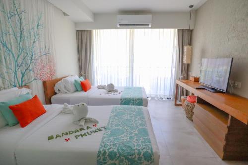 a hotel room with two beds and a television at Bandara Beach Resort, Phuket in Panwa Beach