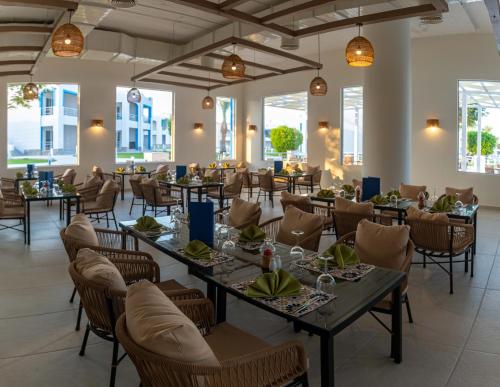 una sala da pranzo con tavoli, sedie e finestre di Casa Blue Resort a Marsa Alam