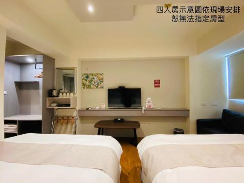 a hotel room with two beds and a flat screen tv at Dazz Inn in Taichung
