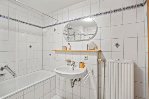 a bathroom with a sink and a tub and a mirror at Louise's City Apartment an der Uferpromenade in Friedrichshafen