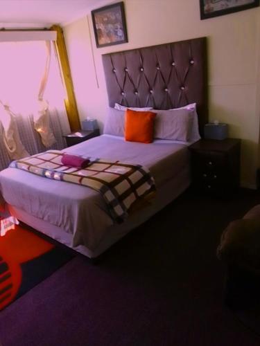 - une chambre avec un grand lit et un oreiller orange dans l'établissement MOFFAT GUEST HOUSE, à Randfontein