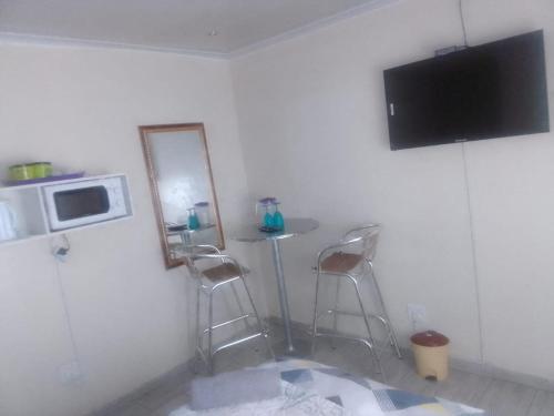 une cuisine avec une table et deux tabourets ainsi qu'une télévision dans l'établissement MOFFAT GUEST HOUSE, à Randfontein
