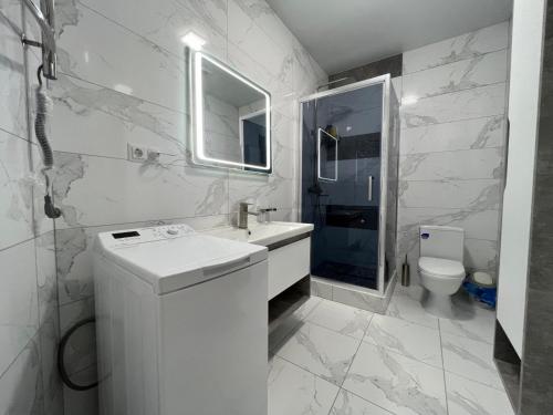 a white bathroom with a sink and a toilet at Arcadia Adelina in Odesa