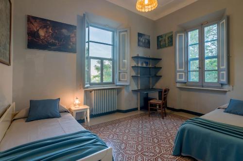 a bedroom with two beds and a chair and windows at Villa Liberty in Osimo