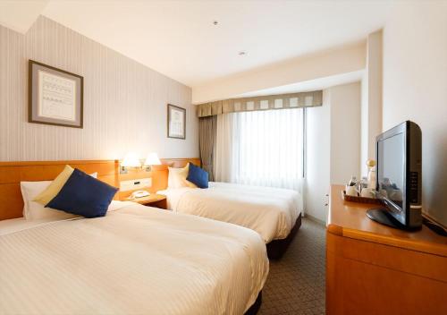 a hotel room with two beds and a flat screen tv at Kanazawa New Grand Hotel Premier in Kanazawa