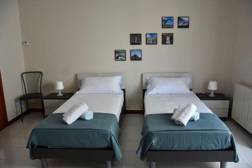 two beds in a room with pictures on the wall at Casa San Martino in Castiglione di Sicilia