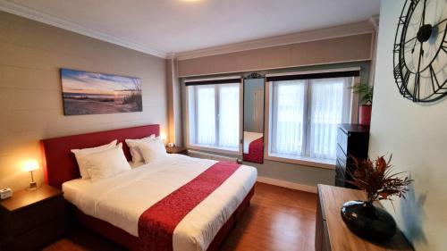 ein Schlafzimmer mit einem großen Bett und zwei Fenstern in der Unterkunft Hotel Cardiff in Ostende
