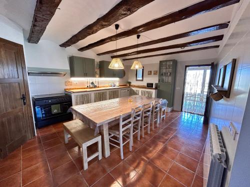 una cocina con una gran mesa de madera y sillas en Masía Casa Rullo, en Allepuz