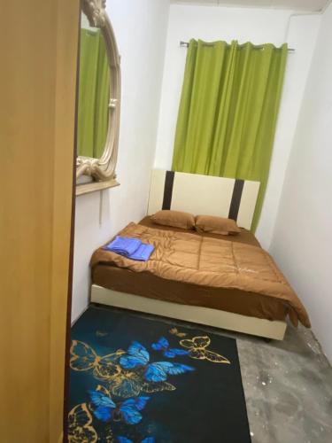 um pequeno quarto com uma cama com uma cortina verde em Cik Misi Homestay (2) em Sik
