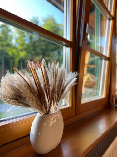 a white vase with dried grass in a window at Dorfpension Mariahilfberg in Gutenstein