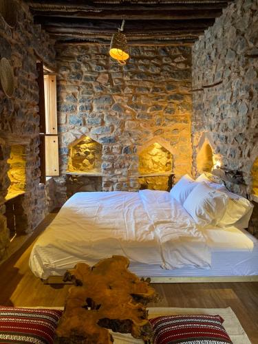 a bedroom with a large bed in a stone wall at Hanging Terraces المدرجات المعلقة in Al ‘Aqar