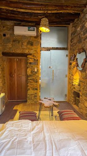 a bedroom with a bed and a stone wall at Hanging Terraces المدرجات المعلقة in Al ‘Aqar