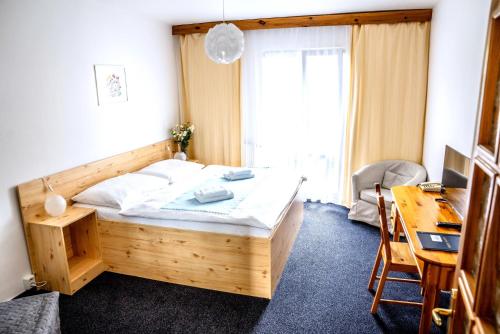 a bedroom with a wooden bed and a desk and a desk at Hotel Gong in Štramberk