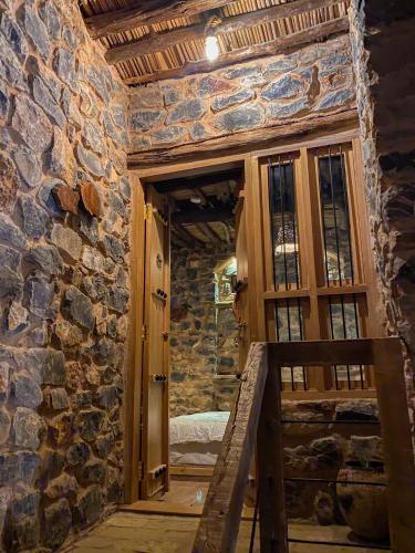 a room with a stone wall and a wooden door at Hanging Terraces المدرجات المعلقة in Al ‘Aqar