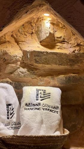 a basket of towels sitting next to a stone wall at Hanging Terraces المدرجات المعلقة in Al ‘Aqar