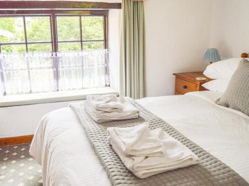 a bedroom with two towels on a bed with a window at Windbury Cottage in Bideford