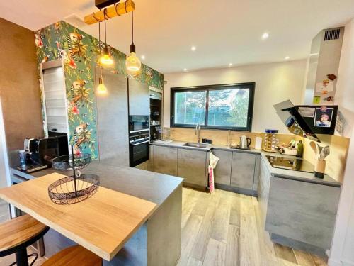 a large kitchen with a table and a counter at Villa avec piscine proche plages in Vaux-sur-Mer