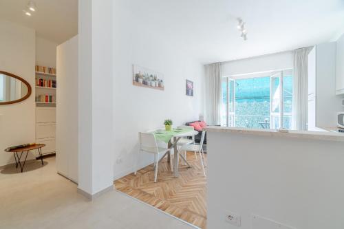a white kitchen with a table and a dining room at Asti Comfy Apartment - Private Parking! in Asti