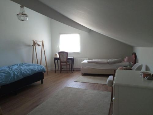 a bedroom with two beds and a desk and a window at The Cherriehouse in Gingelom
