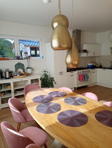 a kitchen with a wooden table and pink chairs at The Cherriehouse in Gingelom