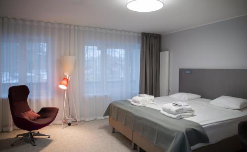 a bedroom with a bed and a chair and a lamp at Wasa Historical 1938 Boutique Hotel in Pärnu
