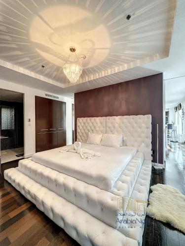 a bedroom with a large white bed with a large headboard at La Casa By Arabian Nights - City View - Bespoke Design in Dubai